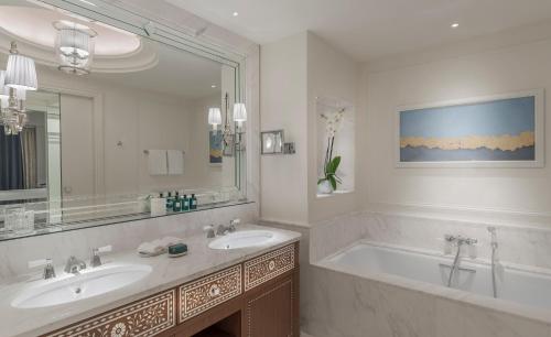 فندق فور سيزونز الدوحة في الدوحة: حمام به مغسلتين وحوض استحمام ومرآة كبيرة