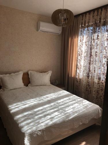 a bedroom with a bed and a window with curtains at Apartment FREEDOM in Shkorpilovtsi