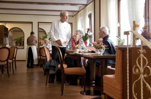 Um homem num restaurante com pessoas sentadas à mesa. em Ferienapartments Schnibbe em Bad Lauterberg