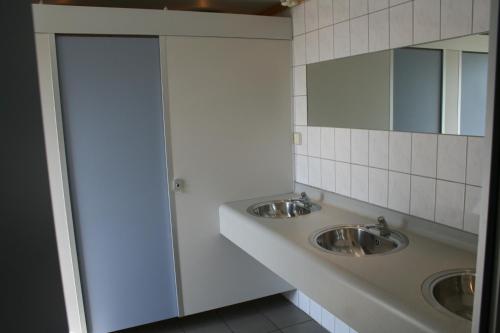 a bathroom with two sinks and two mirrors at Shepherds hut (Pipowagen) in Oostvoorne
