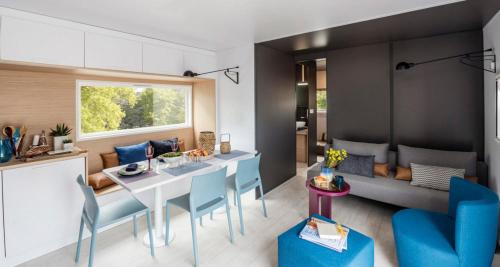 een keuken en een woonkamer met een tafel en blauwe stoelen bij Camping Le Ventadour in Meyras