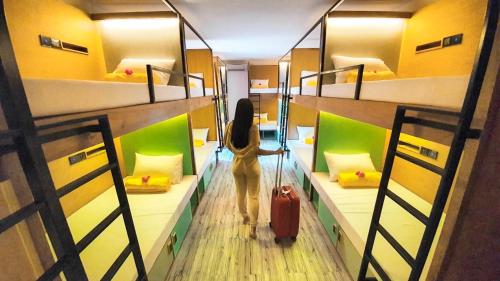 a woman walking through a room with two bunk beds at Stellar Capsules in Seminyak