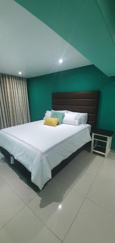 1 dormitorio con 1 cama grande y pared verde en Tertius Lodge And House, en Nelspruit
