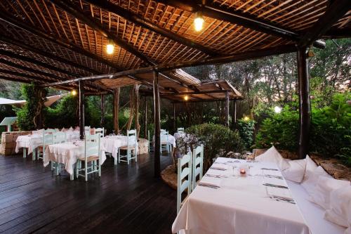 uma sala de jantar com mesas brancas e cadeiras brancas em Green Park Hotel em Porto Cervo