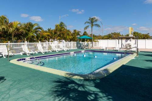 uma grande piscina com cadeiras e árvores em Sunshine Inn & Suites Venice, Florida em Venice