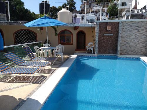 a swimming pool with chairs and an umbrella at Hotel y Bungalows Olivares in Acapulco