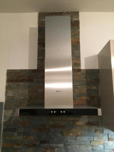a stone fireplace with a stainless steel stove at Stadthaus Artur - Apartment Valencia in Remscheid