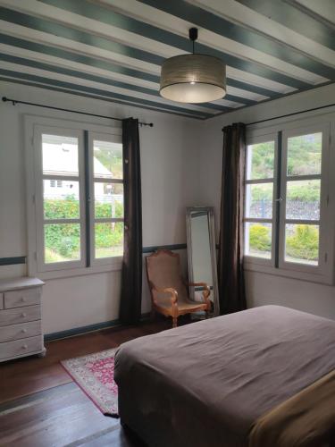 a bedroom with a bed and two windows and a chair at Les Terrasses de Cilaos in Cilaos