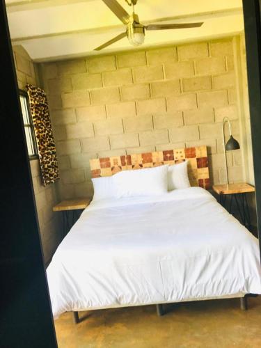 a bedroom with a white bed with a ceiling fan at CÁLIDO COSMOS HOTEL in Cholula