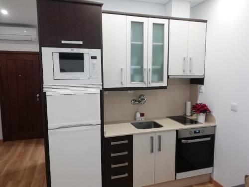 a kitchen with white cabinets and a sink and a microwave at Apartment in the historic center of Porto in Porto