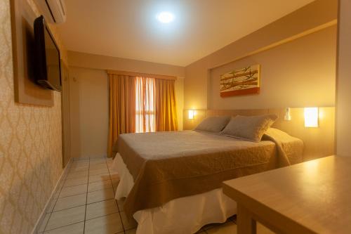 a hotel room with a bed and a television at Paradise Flat in Natal