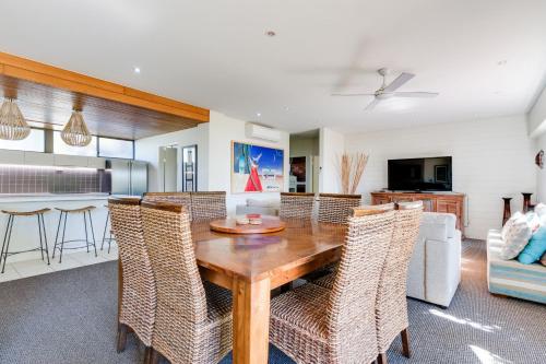 a kitchen with a table, chairs and a refrigerator at Nautilus Beachfront Villas & Spa in Coffs Harbour