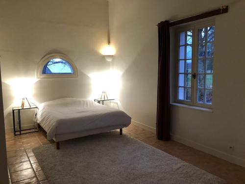 ein Schlafzimmer mit einem Bett mit zwei Lampen und einem Fenster in der Unterkunft Les Gîtes du Cormier in Sambin