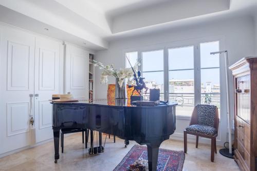 - un grand piano noir dans une pièce avec fenêtres dans l'établissement Art Deco Luxury Apartment with Breath Taking View on Cannes Bay by Olidesi, à Cannes