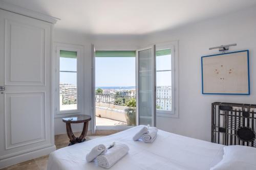- une chambre avec un lit doté de draps blancs et de fenêtres dans l'établissement Art Deco Luxury Apartment with Breath Taking View on Cannes Bay by Olidesi, à Cannes