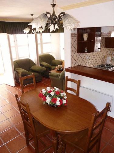 a kitchen and dining room with a table with flowers on it at Apartamentos Os Descobrimentos in Burgau