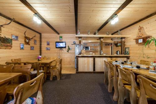 a dining room with wooden walls and tables and chairs at Хата Різьбяра in Beloberëzka