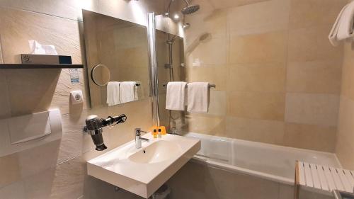 ein Badezimmer mit einem Waschbecken, einer Dusche und einer Badewanne in der Unterkunft Maxhotel in Lindau
