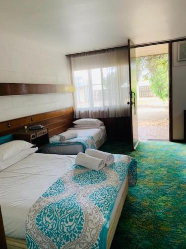 a hotel room with two beds and a sliding glass door at Caledonian Hotel Motel in Hamilton