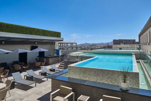 a swimming pool on the roof of a building with lounge chairs at Ramada Encore by Wyndham Chihuahua Distrito 1 in Chihuahua