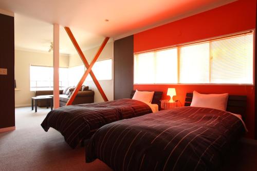 伊東市にあるビーチ コミューン シンプルース（大人専用）の赤い壁と窓が備わる客室で、ベッド2台が備わります。