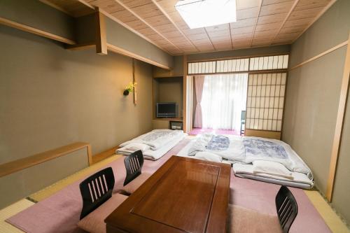 two beds in a room with a table and chairs at Kyonoyado Kagihei in Kyoto
