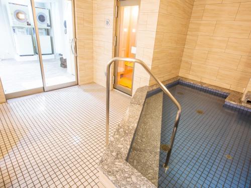 baño con ducha a ras de suelo y puerta de cristal en Kuretake Inn Ogaki Ekimae, en Ōgaki