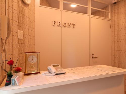 a counter with a phone and a clock on it at Hotel Asahi Grandeur Fuchu in Fuchu