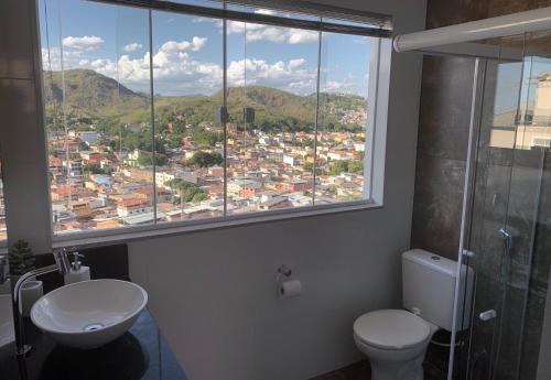 baño con aseo y ventana con vistas. en Loft Sopro da Serra, en São João del Rei