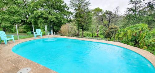 a swimming pool with two blue chairs in a yard at Serendipity On Barrington in Barrington