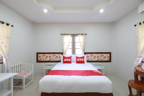 Schlafzimmer mit einem großen Bett mit roter und weißer Bettwäsche in der Unterkunft OYO 553 Kongsup Resort in Lamphun