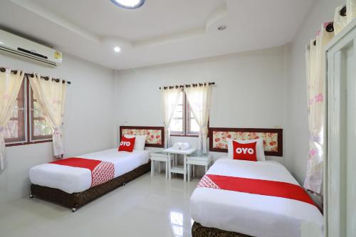 a bedroom with two beds with red and white sheets at OYO 553 Kongsup Resort in Lamphun