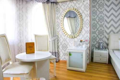 Habitación con cama, mesa y espejo. en Altair Hotel en Shymkent