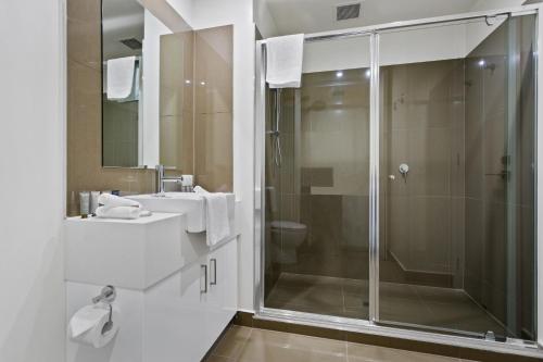 a bathroom with a glass shower and a sink at Soho 203 in Geelong