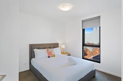 a bedroom with a white bed and a window at Soho 203 in Geelong