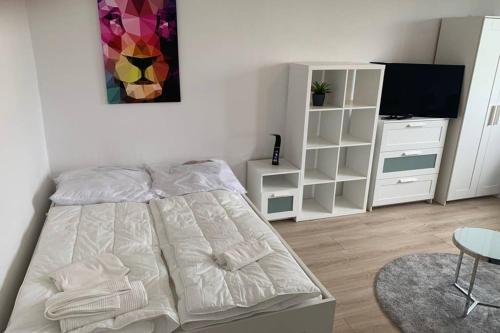 a white bedroom with a bed and a table at 1 Zi-Whg, Netflix, Wifi, Küche, 15min zum Zentrum in Leipzig