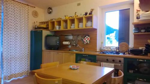 a kitchen with a wooden table and a television at Freetime PinkAlps in Arabba