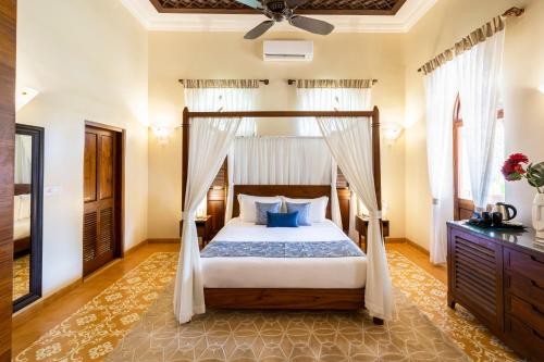 a bedroom with a canopy bed with blue pillows at amã Stays & Trails Villa Siolim, Goa in Siolim