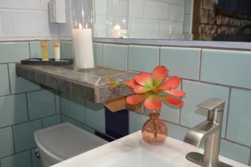 a bathroom with a sink with a red flower in a vase at Lariat Motel in Hardin