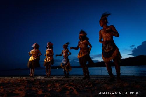 un grupo de artistas en la playa por la noche en Meridian Adventure Marina Club & Resort en Saonek