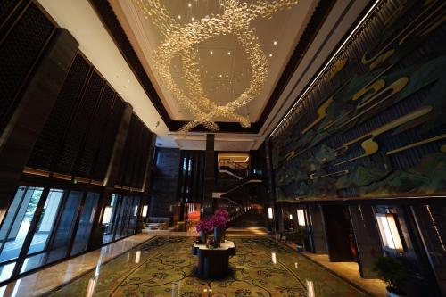 a lobby with a chandelier and flowers on a table at Vignette Collection Haikou Yatter Hotel by IHG in Haikou