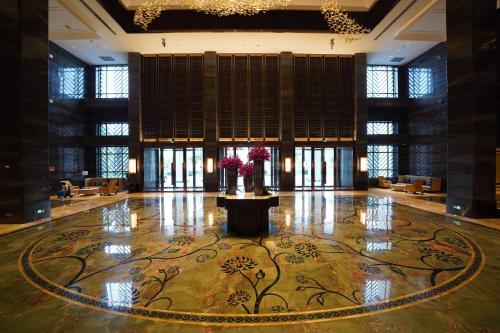 a lobby with a table and flowers in the middle at Vignette Collection Haikou Yatter Hotel by IHG in Haikou