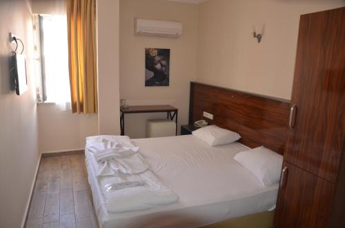 a bedroom with a white bed with a wooden headboard at Marka Hotel in Antalya