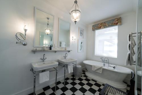 a bathroom with two sinks and a tub and mirrors at Drostdy Hotel in Graaff-Reinet