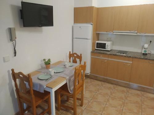 a kitchen with a table with chairs and a microwave at BUHARDILLA PARA DOS EN CAN MINGU in Besalú