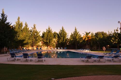 een groep stoelen en een zwembad bij Hotel El Carmen in Puente-Genil