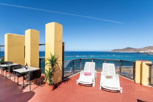 a balcony with chairs and tables and the ocean at Apartamentos Colón Playa in Las Palmas de Gran Canaria