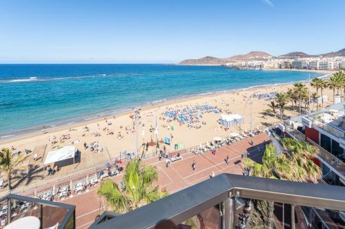a beach filled with lots of beach chairs and umbrellas at Apartamentos Colón Playa in Las Palmas de Gran Canaria