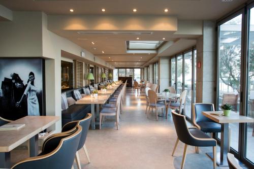 ein Restaurant mit Tischen, Stühlen und Fenstern in der Unterkunft Golden Star City Resort in Peraia