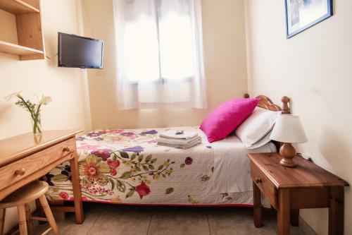 a bedroom with a bed with pink pillows and a window at Apartamentos Maribel in Calaceite